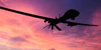 Silhouette of a drone against a colorful sunset.