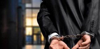 Person in handcuffs wearing a suit in office.