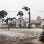 Houses and trees battered by strong winds and rain.