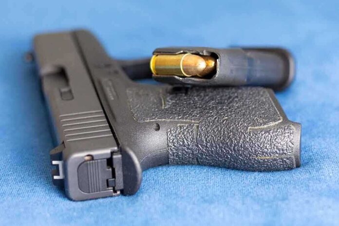 2159542825 featured image Handgun on blue fabric with visible bullet cartridge.