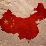 Map of China with flag on textured wall.