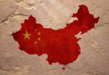 Map of China with flag on textured wall.