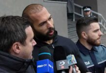 Group of men with microphones outside a building