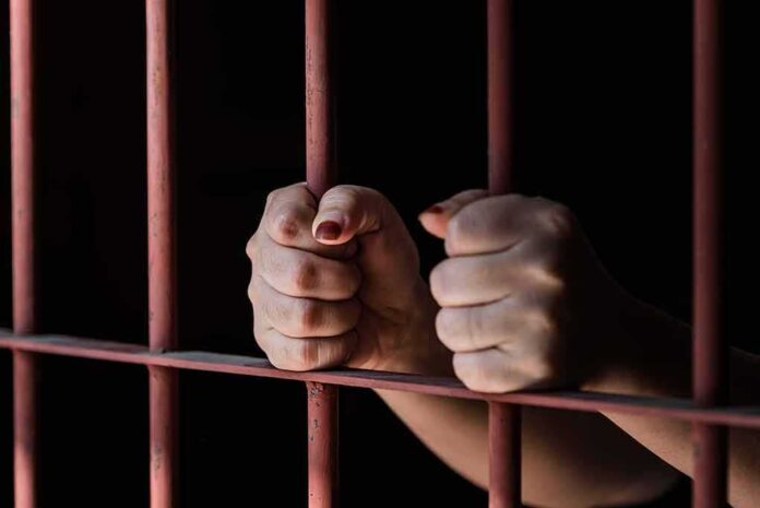 592930874 featured image Hands gripping metal prison bars tightly