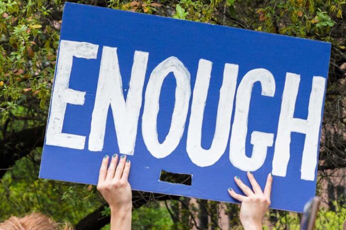 1208630905 featured image Hands holding blue sign saying enough