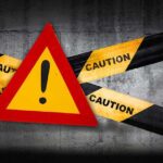 Warning sign with caution tape on concrete background