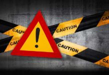Warning sign with caution tape on concrete background