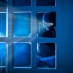 The End to Bots Stealing Your Concert Tickets Masked figure peering through glass door at night