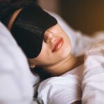 Woman sleeping with eye mask on bed