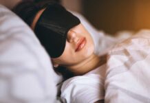 Woman sleeping with eye mask on bed