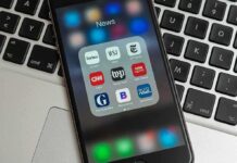 Smartphone displaying news app icons on laptop keyboard