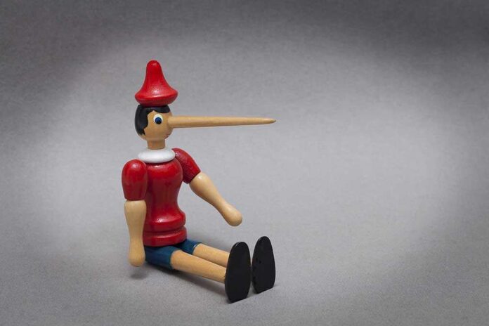 295020104 featured image Wooden puppet with long nose sitting on grey background