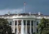 White House with American flag and fountain, stormy sky