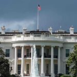 White House with American flag and fountain, stormy sky
