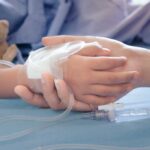 Child hand with IV held by adult