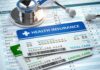 Stethoscope and health insurance cards on medical chart.
