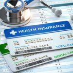 Stethoscope and health insurance cards on medical chart.