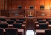 Empty courtroom with wooden furniture and black chairs