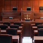 Empty courtroom with wooden furniture and black chairs