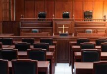 Empty courtroom with wooden furniture and black chairs
