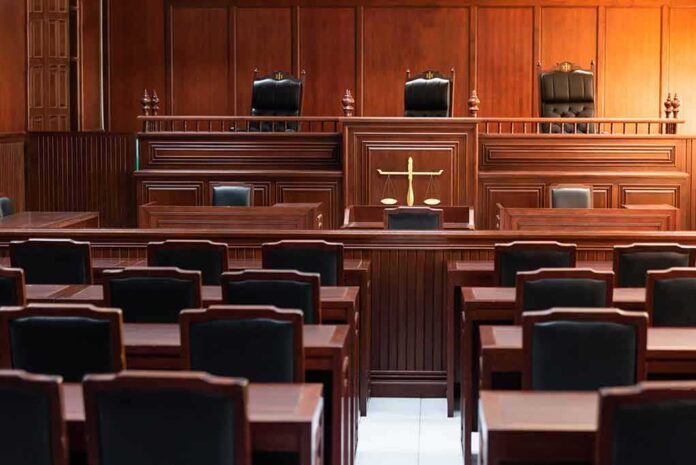 1324425602 featured image Empty courtroom with wooden furniture and black chairs