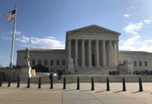 US Supreme Court Building with flag and people outside