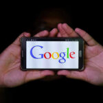Hands holding smartphone displaying Google logo