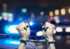 Handcuffed hands raisedpolice cars with lights on