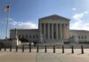 Supreme Court building with flag and people outside