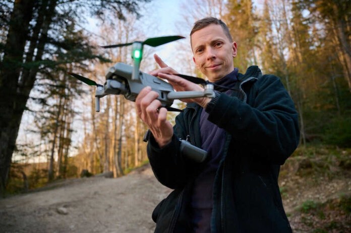 Person holding a drone in a forest