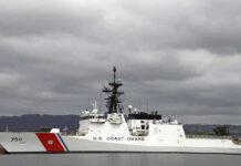 A US Coast Guard ship docked under cloudy skies