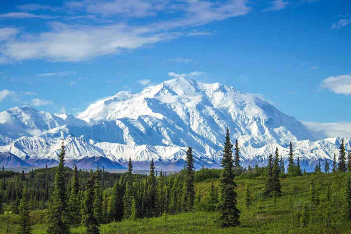1068590996 Snow covered mountain under blue sky with green foreground