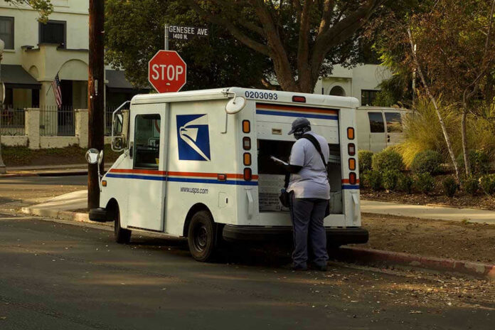 USPS mail carrier at truck near stop sign