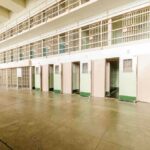 Interior view of a prison cell block with empty cells and security bars