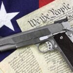 Transgender GUN BAN Proposed – Is This Against The CONSTITUTION? A handgun placed on top of the U.S. Constitution and an American flag