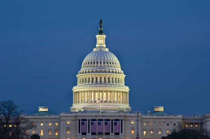 The U.S. Capitol building illuminated at night with American flags displayed