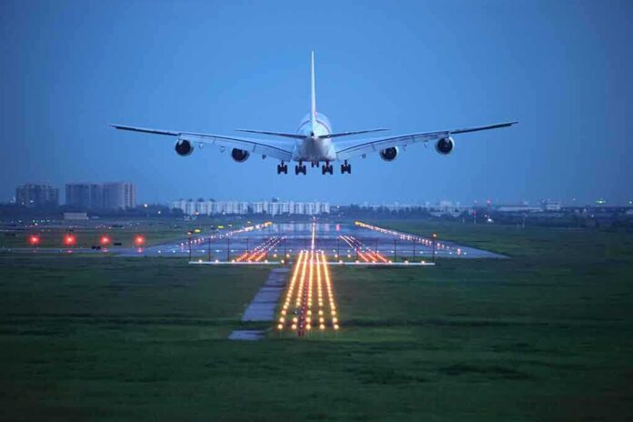 An airplane approaching the runway at night with landing lights illuminated