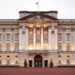 Front view of Buckingham Palace with illuminated facade and British flag