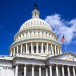 The U.S. Capitol building with a dome and American flag against a blue sky