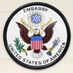 Seal of the United States Embassy featuring an eagle and the American flag