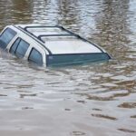 A partially submerged vehicle in floodwaters