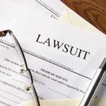 Lawsuit papers with glasses and pen on table.