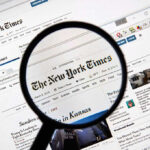 Magnifying glass over The New York Times website.
