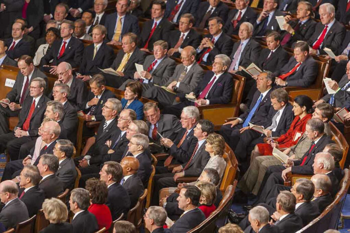 Audience of officials sitting and reading documents in auditorium.