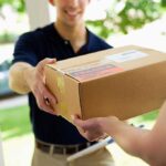 A delivery person handing a package to a customer at their doorstep