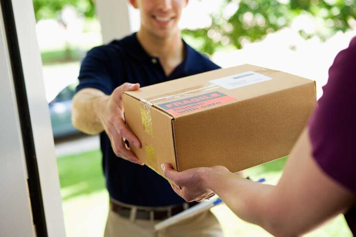 shutterstock_171790418.jpg A delivery person handing a package to a customer at their doorstep