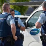 Three police officers discussing near a police vehicle