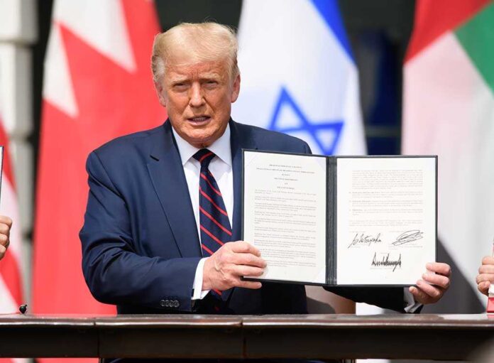A man holding a signed document during a diplomatic event