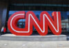 Noem Embarrasses CNN Host on Air – EXPLOSIVE Clash! Large red CNN sign outside building entrance.