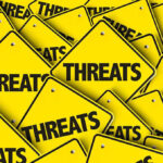 Yellow warning signs with the word THREATS.
